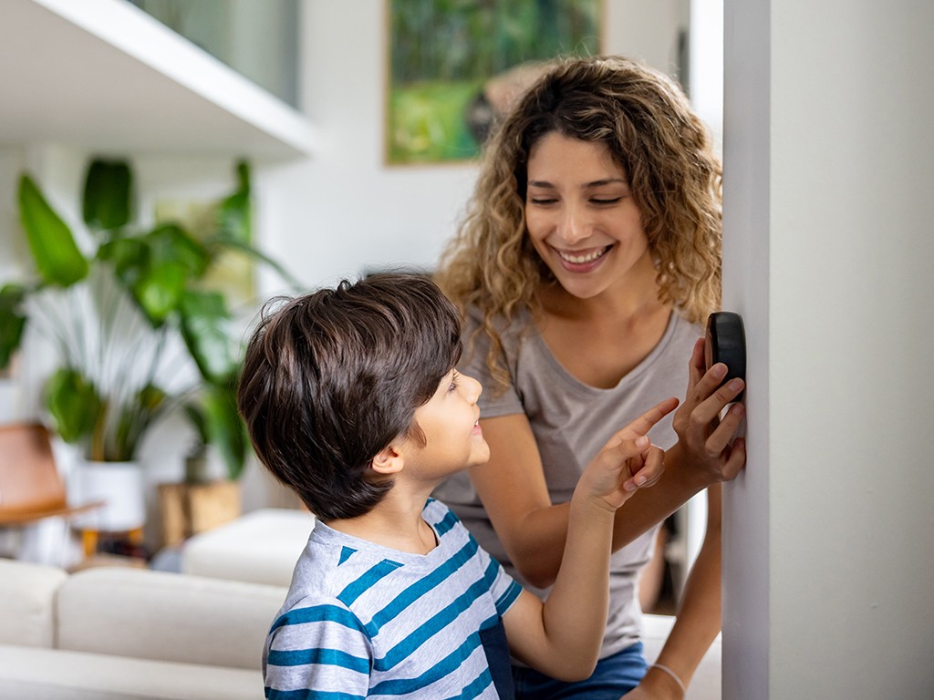 A mom shows her son how to properly set a thermostat.